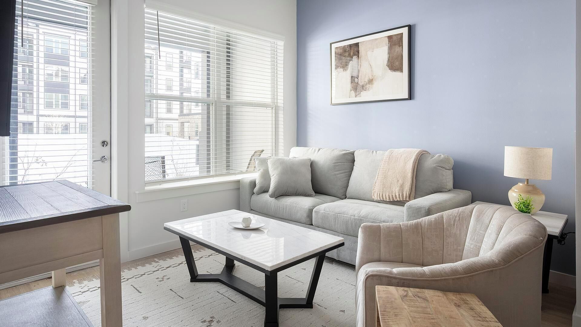 En stue med sofa, lænestol, sofabord og en lampe.
