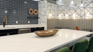Eine moderne Küche mit einer großen Kochinsel, einer schwarz-weißen Spritzschutzwand und Pendelleuchten.