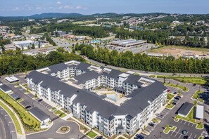A multi-story hotel with a central courtyard, parking areas, and a view of the surrounding landscape. - Landing | Modern 2BD, Courtyard, Gym (Little Rock)
