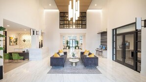Eine geräumige Lobby mit einer Rezeption, zwei Sofas mit Kissen, einem Couchtisch und einem großen Fenster.