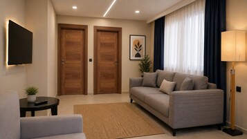 Uma sala de estar moderna com sofá, uma mesinha com uma planta, televisão na parede e duas portas de madeira.
