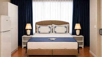 Ein Hotelzimmer mit einem Bett, zwei Nachttischen, einer Lampe, einem Kleiderschrank und einem fenster mit Vorhängen.