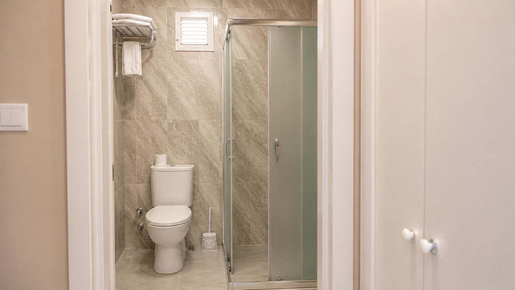 A bathroom with a toilet, a shower, and a glass door.