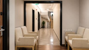Un vestíbulo de hotel con una recepción, una escalera y zonas de estar.