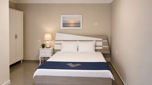Habitación de hotel con cama, mesita de noche, lámpara y un cuadro en la pared.