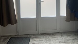 A room with a sliding glass door, a doormat, and a light-colored floor.