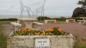 A garden area with a stone bench, a metal sculpture of giraffes, and a sign reading 'SQUARE LA GUICHARDE.'