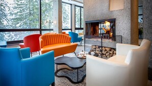 Ein moderner Lounge-Bereich mit Kamin, großen Fenstern und farbenfroher Sitzmöbel.