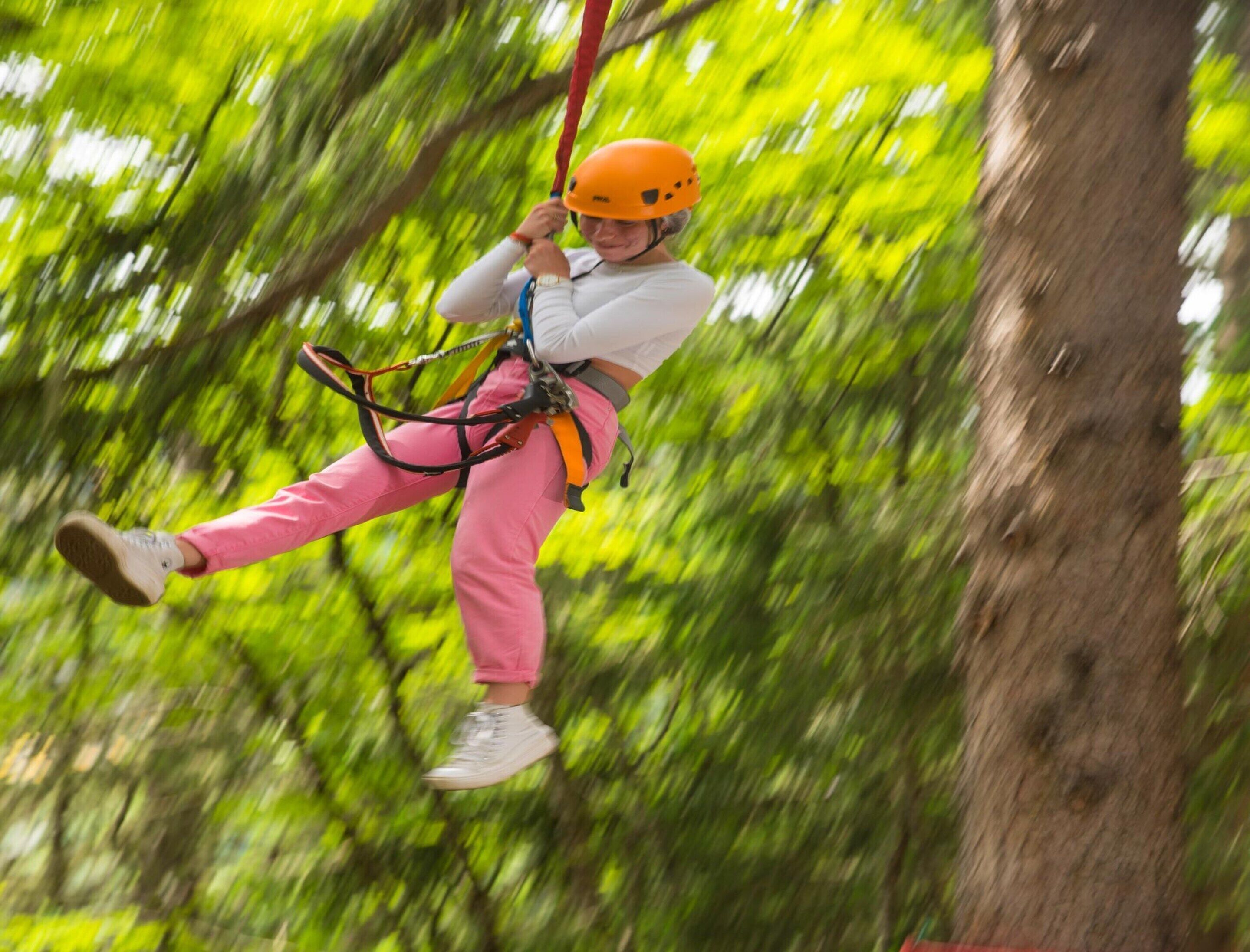 A person zip-lining through a forested area.