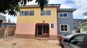 A two-story residential building with a gated entrance, a car parked in the driveway, and a satellite dish on the roof. - Family home in Adenta, Accra in a quite neighbourhood, 30 mins from the Airport. (Greater Accra Region)