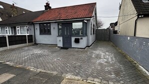 A residential property with a paved driveway, a red-tiled roof, and a number '82' on the building. - Charming Bungalow Rental in Rainham Comfort and Convenience (Rainham)