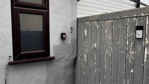 A house with a window, a doorbell, and a weathered fence. - Charming Bungalow Rental in Rainham Comfort and Convenience (Rainham)