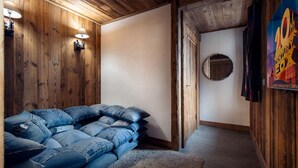 A room with wooden walls, a sofa made of denim, a rug, and a poster on the wall. - Chalet Genepy by Interhome (Peisey-Nancroix)