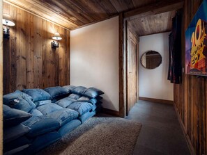 A room with wooden walls, a sofa made of denim, a rug, and a poster on the wall. - Chalet Genepy by Interhome (Peisey-Nancroix)