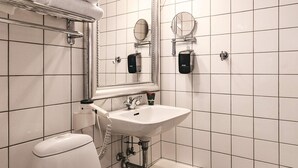 A bathroom with white tiled walls, a sink, a toilet, a towel rack, and two mirrors. - 4 Person Holiday Home in Brovst (Brovst)