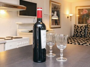 A bottle of wine on a table with two glasses, a kitchen in the background, and a patterned sofa. - 4 Person Holiday Home in Brovst (Brovst)