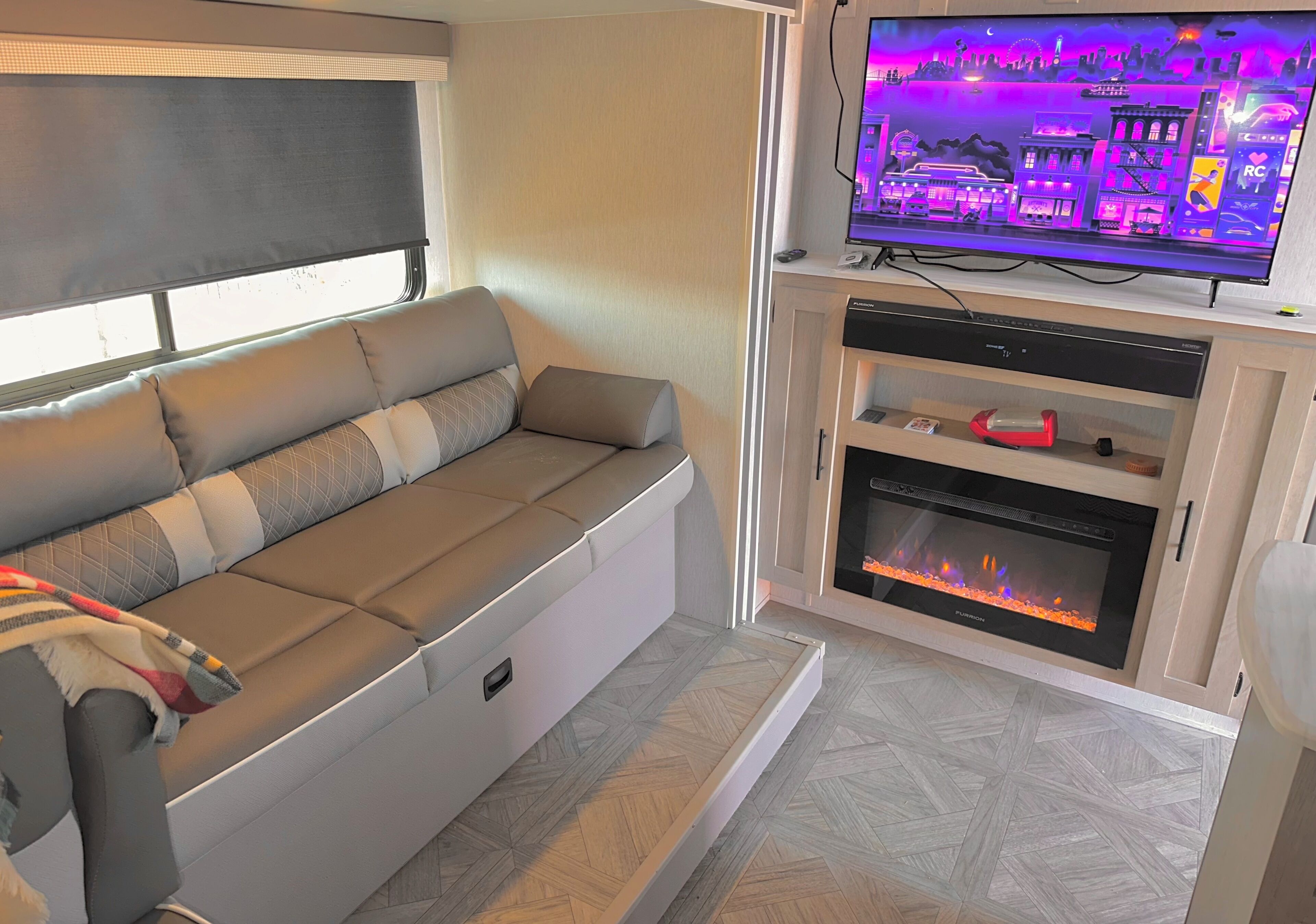 A cozy living area with a sofa, a flat-screen TV, a fireplace, and a cabinet.