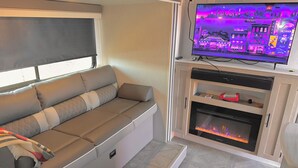 Un salon confortable avec un canapé, un téléviseur à écran plat, une cheminée et un meuble.