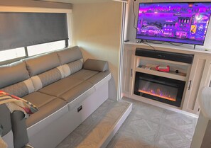 Ein gemütlicher Wohnbereich mit einer Couch, einem Flachbildfernseher, einem Kamin und einem Schrank.