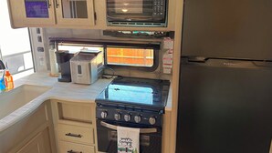 Une cuisine compacte équipée d’un four à micro-ondes, d’un grille-pain, d’une cuisinière et d’un réfrigérateur.