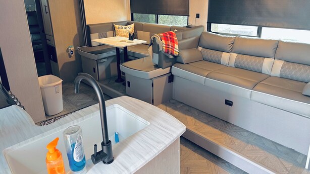 Un intérieur de camping-car compact comprenant un coin cuisine, un espace repas et un coin salon avec une fenêtre.