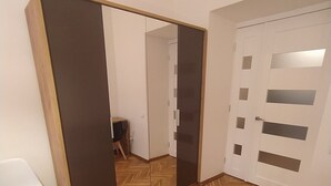 A room with a herringbone wooden floor, a white chair, a mirror, and a door with frosted glass panels.