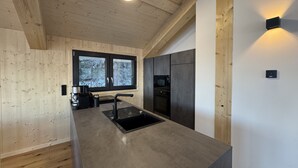 Una cucina moderna con pareti in legno, un'ampia finestra ed elettrodomestici integrati.