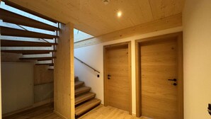 Una scala in legno conduce a un pianerottolo con due porte di legno.