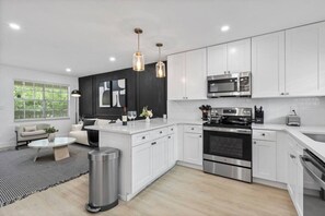 A modern kitchen with white cabinets, stainless steel appliances, and pendant lighting. - Prime Location - Cozy Luxury Suite With Free Parking and Crib in South Tampa!! (Tampa)