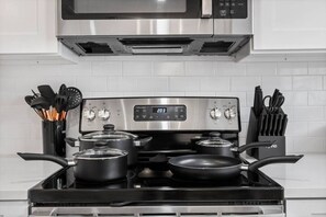 A kitchen with a stove, pots, and a microwave above it. - Prime Location - Cozy Luxury Suite With Free Parking and Crib in South Tampa!! (Tampa)