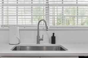 A kitchen with a stainless steel sink, a faucet, and a soap dispenser. - Prime Location - Cozy Luxury Suite With Free Parking and Crib in South Tampa!! (Tampa)
