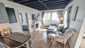 A cozy living area with a sofa, a fireplace, and a television. - Dogs Stay Free! Lakefront Home near Notre Dame (South Bend)