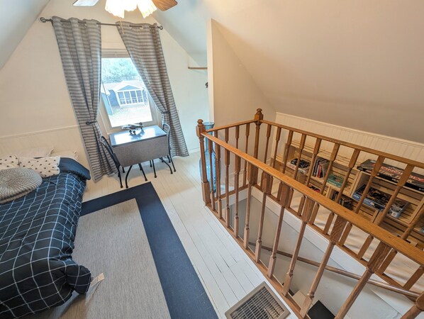A bedroom with a bed, a desk, a window with curtains, a staircase, and a bookshelf. - Dogs Stay Free! Lakefront Home near Notre Dame (South Bend)