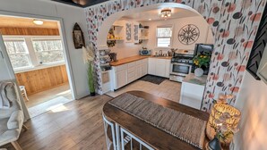 A modern kitchen with white cabinets, a wooden countertop, and a central island. - Dogs Stay Free! Lakefront Home near Notre Dame (South Bend)