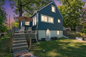 A two-story house with a covered porch, a set of stairs leading to the entrance, and a small front yard. - Dogs Stay Free! Lakefront Home near Notre Dame (South Bend)
