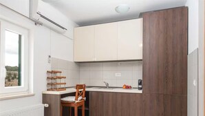 A kitchen with wooden cabinets, a chair, a fruit bowl, and a window. - Seaview Family Villa With Heated Pool (Okrug)