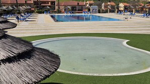 A pool area with lounge chairs and umbrellas, surrounded by buildings with red roofs. - BOAVISTA GOLF RESORT - apartment with large terrace overlooking the GREEN (LAGOS)