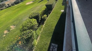 A balcony with a view of a well-maintained lawn, a distant building, and a clear sky. - BOAVISTA GOLF RESORT - apartment with large terrace overlooking the GREEN (LAGOS)