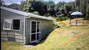 A single-story house with a front door, a small porch, and a covered outdoor area. - A short walk to the beautiful Lake Taupo relax and take in the fabulous views! (Kuratau)