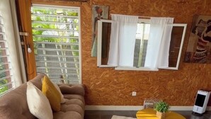 Een woonkamer met een bank, een bijzettafeltje, een plant in pot en een raam met gordijnen.