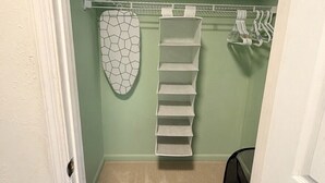 A laundry room with a drying rack, ironing board, and storage shelves. - Sunny Baldwin Park Studio • Walk to Cafés • Near Downtown (Orlando)