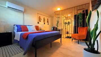 A modern bedroom with a bed, bedside table, lamp, and a large potted plant.