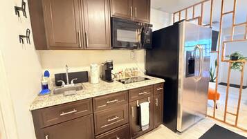 A modern kitchen with dark brown cabinets, stainless steel appliances, and a granite countertop.