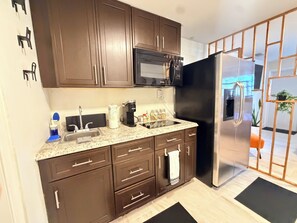 A modern kitchen with dark brown cabinets, stainless steel appliances, and a granite countertop.