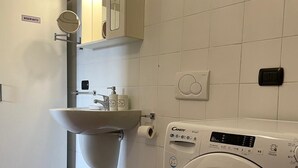 Une petite salle de bain comprenant des toilettes, un lavabo et un lave-linge.