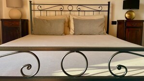 Un lit avec un cadre en métal, deux oreillers, une table de chevet avec une lampe et une petite table de nuit avec une lampe.