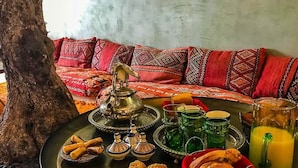 Un décor marocain traditionnel avec un plateau en laiton, des coussins et un arbre.