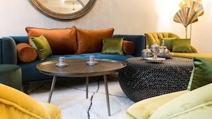 Un salon avec un canapé bleu, une table basse ronde et une lampe décorative.