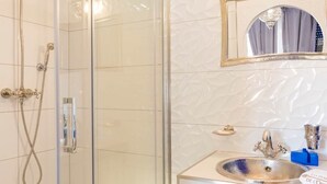 A bathroom with a glass-enclosed shower, a sink with a decorative basin, and a mirror with a decorative frame. - Majorelle room (Tours)