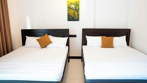 Duas camas de solteiro com roupa de cama branca e almofadas castanhas, um quadro de pássaros na parede e uma cortina à esquerda.